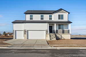 View of front of house featuring concrete driveway, covered porch, an attached garage, and board and batten siding