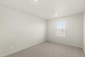 Empty room with light carpet and recessed lighting