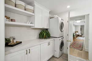 Laundry area featuring cabinet space, estacked washer and dryer, light wood-style floors, and recessed lighting