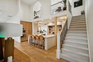 Kitchen featuring a breakfast bar area, light countertops, brown cabinets, a high ceiling, and light wood finished floors