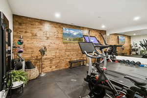 Exercise room featuring dark flooring, wood walls, and recessed lighting