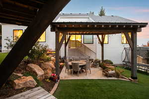 Patio terrace at dusk with a patio area, a lawn, and a trampoline