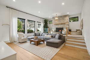 Living room featuring recessed lighting, light wood-style floors, and a stone fireplace
