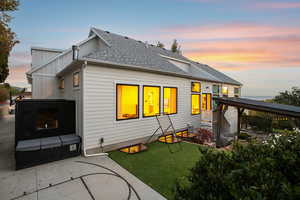 Rear view of house with roof with shingles, a patio area, board and batten siding, and a lawn
