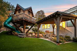 Back of property at dusk featuring a yard, a patio, and a playground