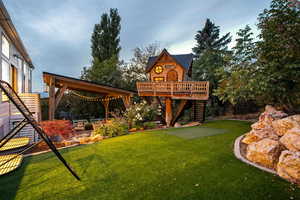 View of grassy yard with a deck, stairway, and a putting green