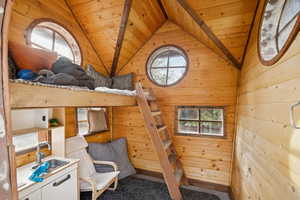 Carpeted bedroom with wood walls, wooden ceiling, and lofted ceiling