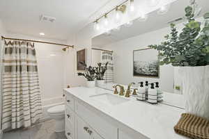 Full bathroom with vanity, shower / bath combo with shower curtain, dark tile patterned floors, and recessed lighting