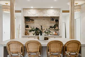 Bar featuring hanging light fixtures, a chandelier, open shelves, and light stone countertops