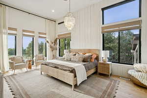 Bedroom featuring a towering ceiling, wood-type flooring, a chandelier, recessed lighting, and wooden walls