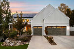 Modern inspired farmhouse with roof mounted solar panels, board and batten siding, concrete driveway, and a garage