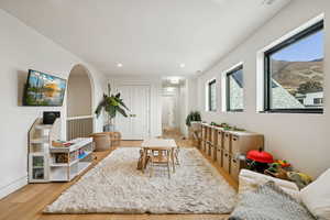 Game room with light wood-style floors, recessed lighting, a mountain view, and arched walkways