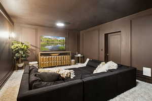 Carpeted home theater with a decorative wall and a textured ceiling