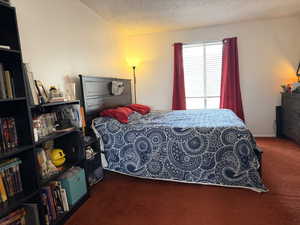 Bedroom with dark carpet and a textured ceiling