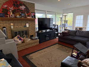 Living room with a brick fireplace, carpet, a textured ceiling, and brick wall