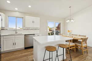 Kitchen with white cabinets, tasteful backsplash, a center island, light wood-type flooring, and dishwasher