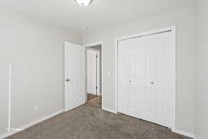 Unfurnished bedroom with dark colored carpet and a closet
