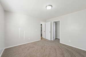Unfurnished bedroom with carpet floors, a spacious closet, and a textured ceiling