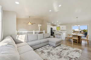 Living area with recessed lighting, lofted ceiling, wood finished floors, a chandelier, and a ceiling fan