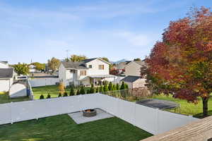 Fenced backyard with a residential view, a trampoline, and a fire pit