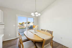 Dining room featuring dark wood-type flooring, a chandelier, and vaulted ceiling