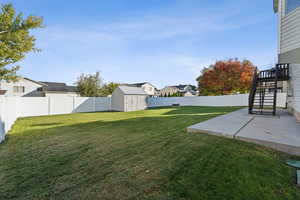 Fenced backyard with a shed, a patio, a residential view, and stairway