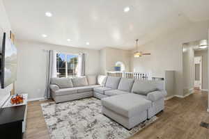 Living room featuring lofted ceiling, light wood-type flooring, and recessed lighting