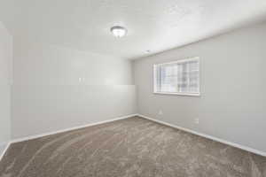 Spare room featuring a textured ceiling and carpet