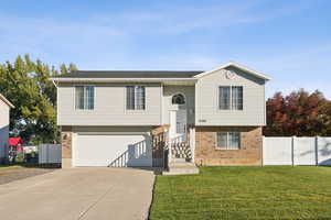 Raised ranch featuring brick siding, driveway, a garage, and a shingled roof