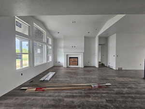 Unfurnished living room with a fireplace, dark wood-type flooring, and a textured ceiling