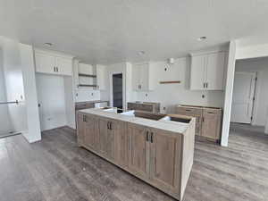 Kitchen featuring a center island, wood finished floors, white cabinets, and a textured ceiling