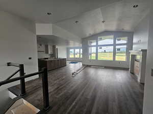 Unfurnished living room with a fireplace, dark wood-style flooring, and vaulted ceiling