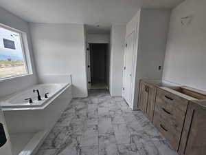 Full bathroom featuring a bath, a closet, and light marble finish flooring