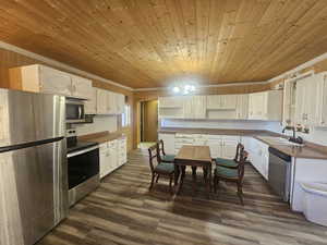 Kitchen featuring stainless steel appliances, white cabinetry, new flooring, crown molding & tongue & groove wood ceiling