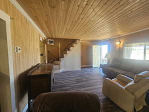 Living area featuring wood walls, new flooring, stairway to loft, tongue & groove ceiling, and crown molding