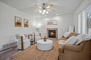 Living room with a tiled fireplace, wood finished floors, a ceiling fan, and recessed lighting