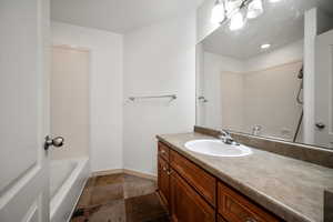 Bathroom with vanity, a tub, stone tile flooring, and recessed lighting