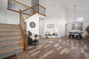 Living room with high vaulted ceiling, hardwood / wood-style floors, a chandelier, and stairway