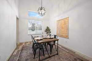 Dining area featuring high vaulted ceiling, wood finished floors, and a chandelier
