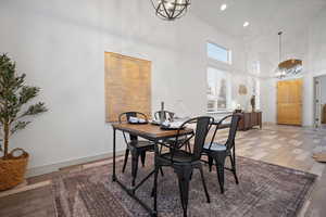 Dining room with a chandelier, a towering ceiling, light wood-style floors, and recessed lighting