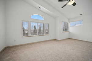 Empty room featuring carpet flooring, high vaulted ceiling, and a ceiling fan