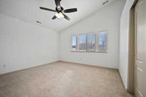 Empty room featuring light colored carpet, ceiling fan, and high vaulted ceiling