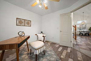 Home office featuring light wood-type flooring, a chandelier, lofted ceiling, and ceiling fan