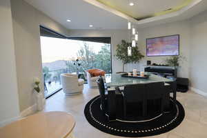 Dining area with recessed lighting, light tile patterned floors, and a raised ceiling