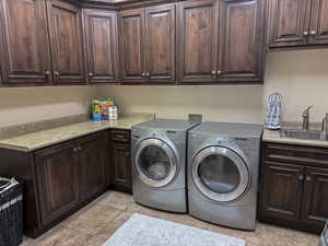 Laundry room with cabinet space, light tile patterned floors, and washer and clothes dryer