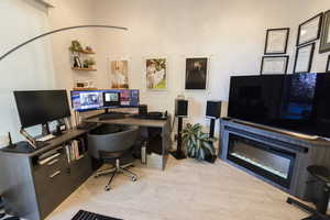 Office space featuring light wood-type flooring and a glass covered fireplace