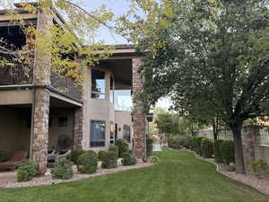 Rear view of property with a balcony, stucco siding, stone siding, and a patio