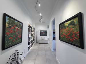 Hallway with crown molding, rail lighting, and light tile patterned floors