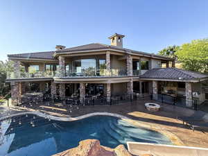 Outdoor pool with a fire pit, a balcony, and a patio