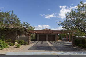 View of front facade with driveway, a garage, stone siding, a carport, and stucco siding